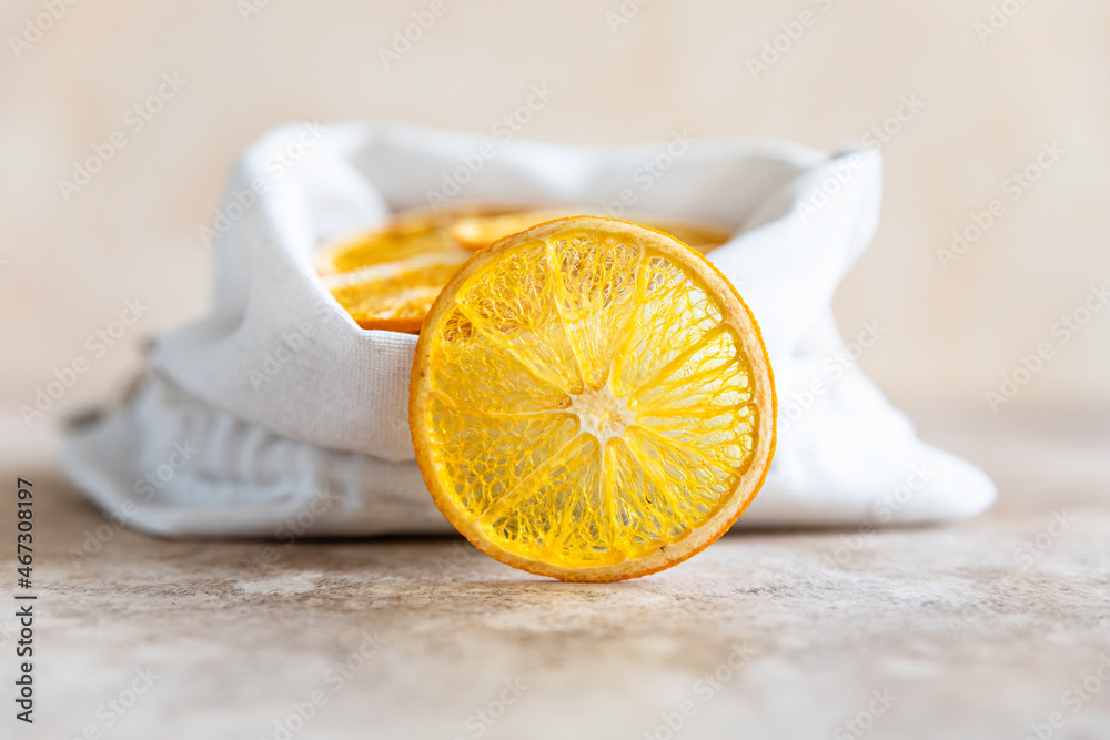 Wall mural Organic dried orange chips in eco canvas bag on light concrete background.