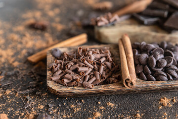 Chocolate pieces, chips and drops with cocoa powder and spices on dark background. Sweet food concept.