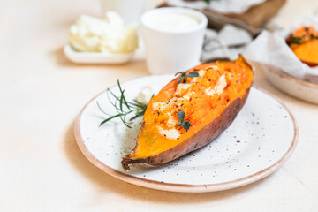 Baked sweet potatoes with mozzarella, herbs and creamy dip on concrete background.