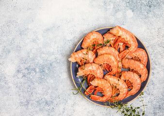 Raw red Argentine shrimps on ceramic plate, blue concrete background. Ocean jumbo shrimps. Top view.