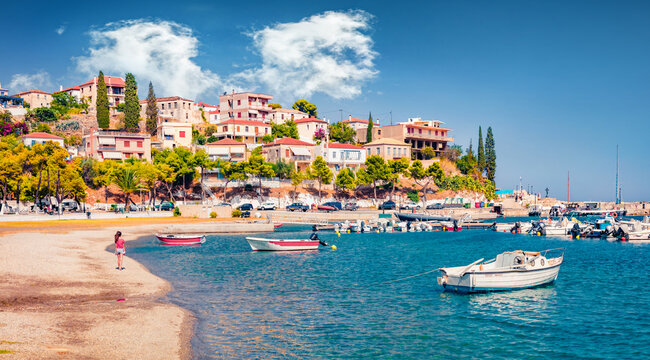 Promenade on the shore of Astros port. Sunny summer seascape of Myrtoan Sea. Picturesque evening scene of Arcadia region, Greece, Europe. Traveling concept background.