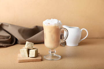 Glass of iced hojicha latte and cubes on beige background
