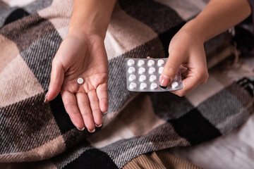 Woman hold blister pack white medical pills tablets pain stomach menstruation periods cycle headache pain insomnia. Lady sick ill cold fever freezing, migraine concept symptoms. Emergency call
