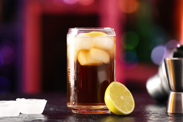 Glass of cold Cuba Libre cocktail on table in bar