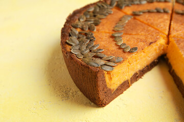 Cut pumpkin pie on yellow background, closeup
