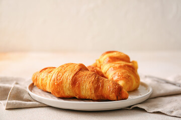 Plate with delicious croissants on white background