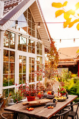 the courtyard of the house with a large wooden table decorated in autumn style. 