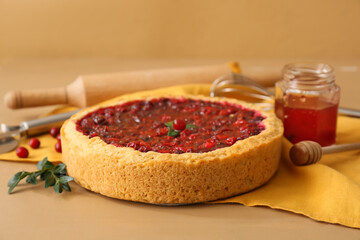 Tasty lingonberry pie and jam on color wooden table