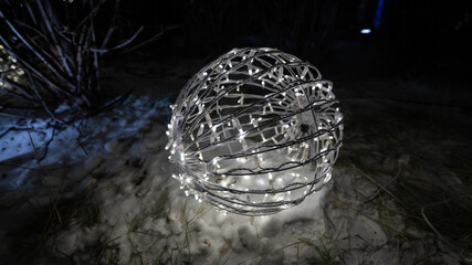Christmas lights in the shape of a ball on the snow.