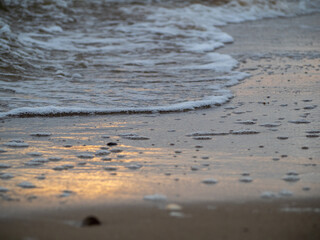 Fototapeta na wymiar Wave with white foamy coastline beach. Sandy shore.