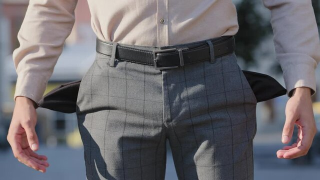 Close-up unrecognizable man turning empty pockets in male pants. Poor businessman has money problems finances crisis economic unemployment non-payment. Cropped view guy need salary debt loan help