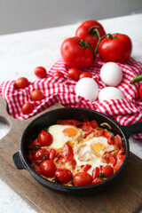 Frying pan with tasty Shakshouka on table