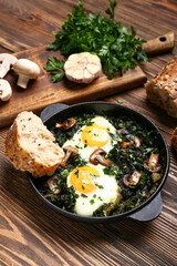 Frying pan with tasty Shakshouka on wooden background