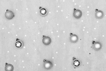 Silver Christmas balls laid out on the table with sequins in the form of stars. Gray background. Christmas or new year pattern