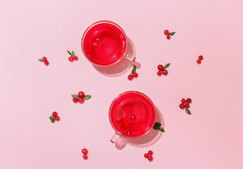 Cups of tasty lingonberry tea on pink background