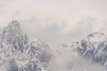 Wilder Kaiser in Tirol Österreich mit ersten Schnee im Jahr umhüllt von Wolken und Nebelschwaden.