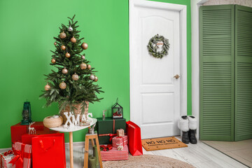 White door with wreath, Christmas tree and gifts near green wall