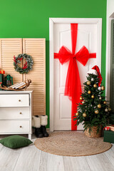 White door with red bow and Christmas tree in room