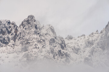 Wilder Kaiser in Tirol Österreich mit ersten Schnee im Jahr umhüllt von Wolken und Nebelschwaden.