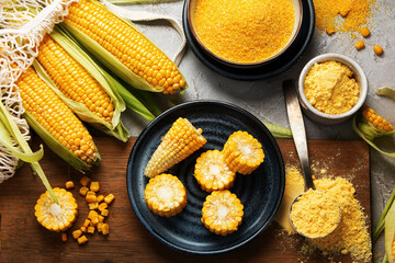 Corncobs and corn groats on gray background.