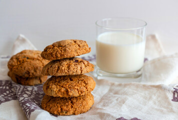 Oatmeal cookies with milk on white background and linen towel with purple snowflakes
