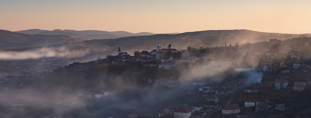 Fototapeta premium Sic, Romania. Foggy sunset over the small village, Transylvania.
