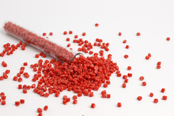 Red granules of polypropylene, polyamide in a measuring beaker and a test tube on a white...