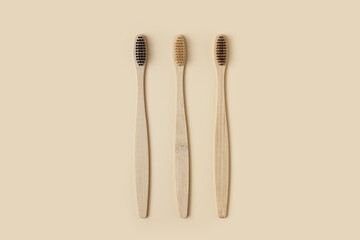 Bamboo wooden three toothbrushes on a beige background. Cleanliness and hygiene of the dental cavity. Minimalism, ecology, no waste and environmental friendliness. copyspace