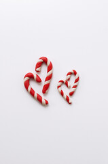 four caramel plasticine canes in the form of hearts of different sizes on a white background