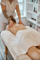 Obraz na płótnie Canvas Professional confident massage master is doing procedures to caucasian woman in minimalistic modern cabinet