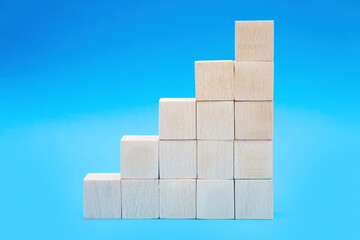 Toy wooden blocks stacked into stairs on blue