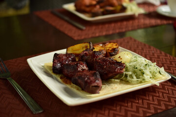 Beef kebab with baked potatoes and fresh onions. A dish on a white plate.