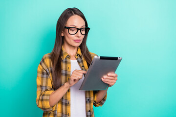 Fototapeta premium Photo of bossy young brunette lady hold tablet wear eyewear yellow shirt isolated on turquoise color background