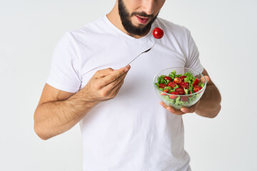 a man in a white t-shirt in a plate with salad a snack healthy food