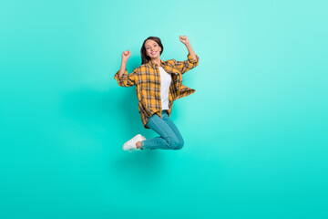 Fototapeta na wymiar Full length photo of mature funky brunette lady jump yell wear shirt jeans shoes isolated on turquoise background