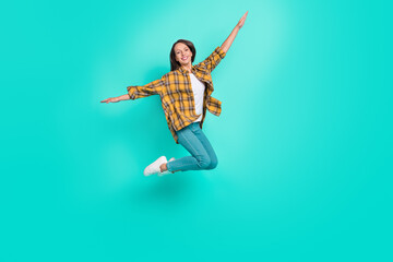 Full body photo of young cool brunette lady jump wear shirt jeans sneakers isolated on turquoise background