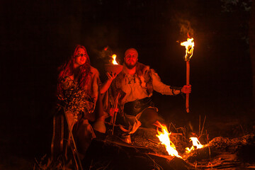 Ancient medieval peoples a man and a woman in historical Viking costumes by the fire in the night...