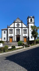Fototapeta na wymiar The facade of a white stone building on a street with a steep rise. Tourist Assamadda. Portugal