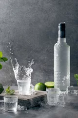 Foto op Plexiglas Bottle of vodka with splash shot glass on concrete background with copyspace.. Vertical format. © Miguel Tamayo 