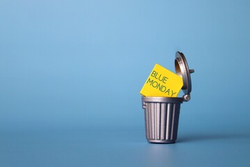 Blue Monday or Monday Blues concept. Wooden cube with text BLUE MONDAY inside dustbin, trash can. Copy space for text