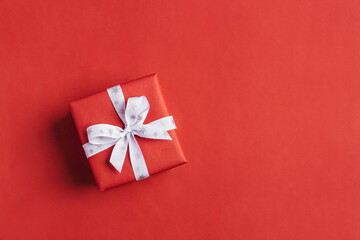 Gift boxe with white bow on a red backdrop.