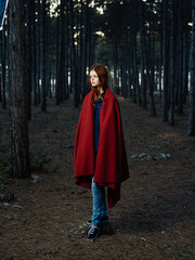 woman in the woods covered herself with a red blanket walk fresh air