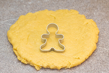 Form for cutting gingerbread men on raw rolled dough on a gray background. Christmas food tradition