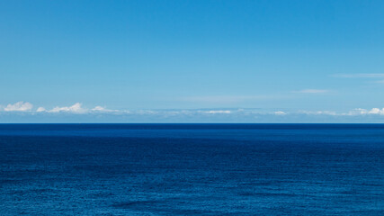 Blue Ionian sea landscape and skyscape wide view in Greece. Bright day with low scenic white clouds over rippled deep blue water surface