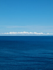 Blue Ionian sea and skyscape vertical view in Greece. Bright day with scenic white clouds over rippled deep blue water surface