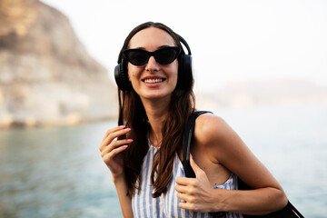 Hot woman relaxing on the sandy beach. Beautiful woman with headphones listening the music.