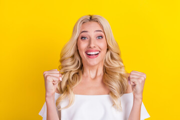 Portrait of attractive lucky cheerful wavy-haired girl rejoicing great news isolated over bright yellow color background