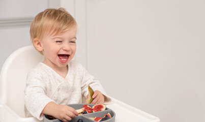 Laughing caucasian blonde baby,eating from silicone plate fresh fruits,berries.Kid self-feed.Happy...