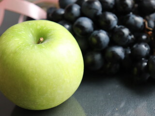 apple with black grapes on a black background