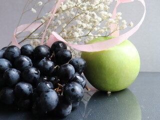 apple with black grapes on a black background